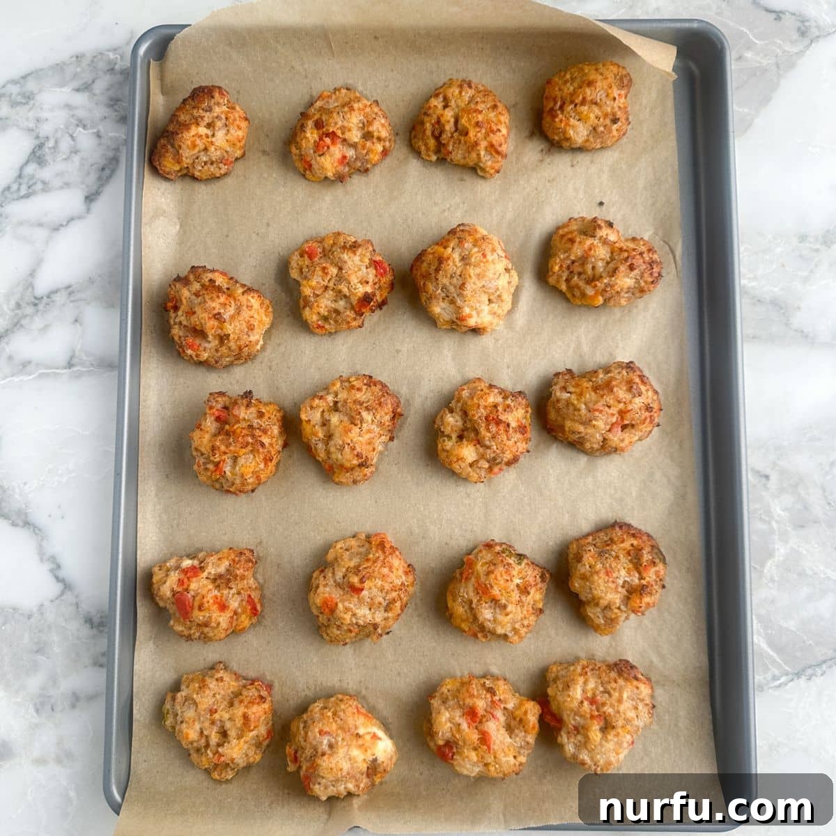 A baking sheet laden with freshly baked, golden-brown Rotel Cream Cheese Sausage Balls, hot and ready to be enjoyed.