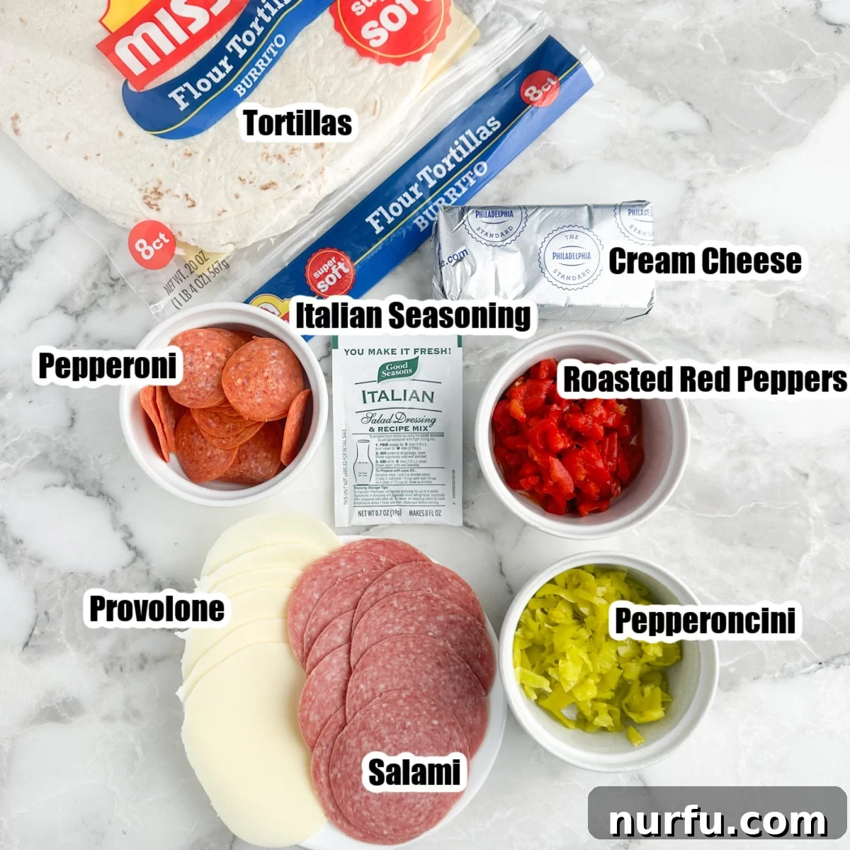 Italian Spiral Bites 3 A vibrant flat lay of all the Italian pinwheel ingredients: tortillas, pepperoni, provolone cheese, salami, softened cream cheese, diced roasted red peppers, and pepperoncini.