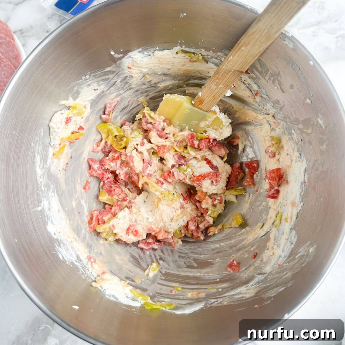 Italian Spiral Bites 4 Close-up shot of a bowl containing the creamy, zesty cream cheese spread, mixed with finely chopped roasted red peppers and pepperoncini.