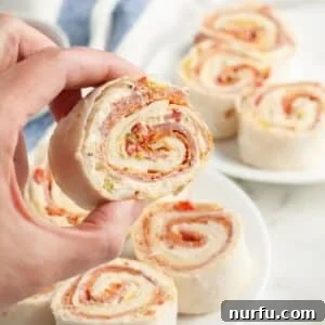 Hand holding an Italian pinwheel appetizer.