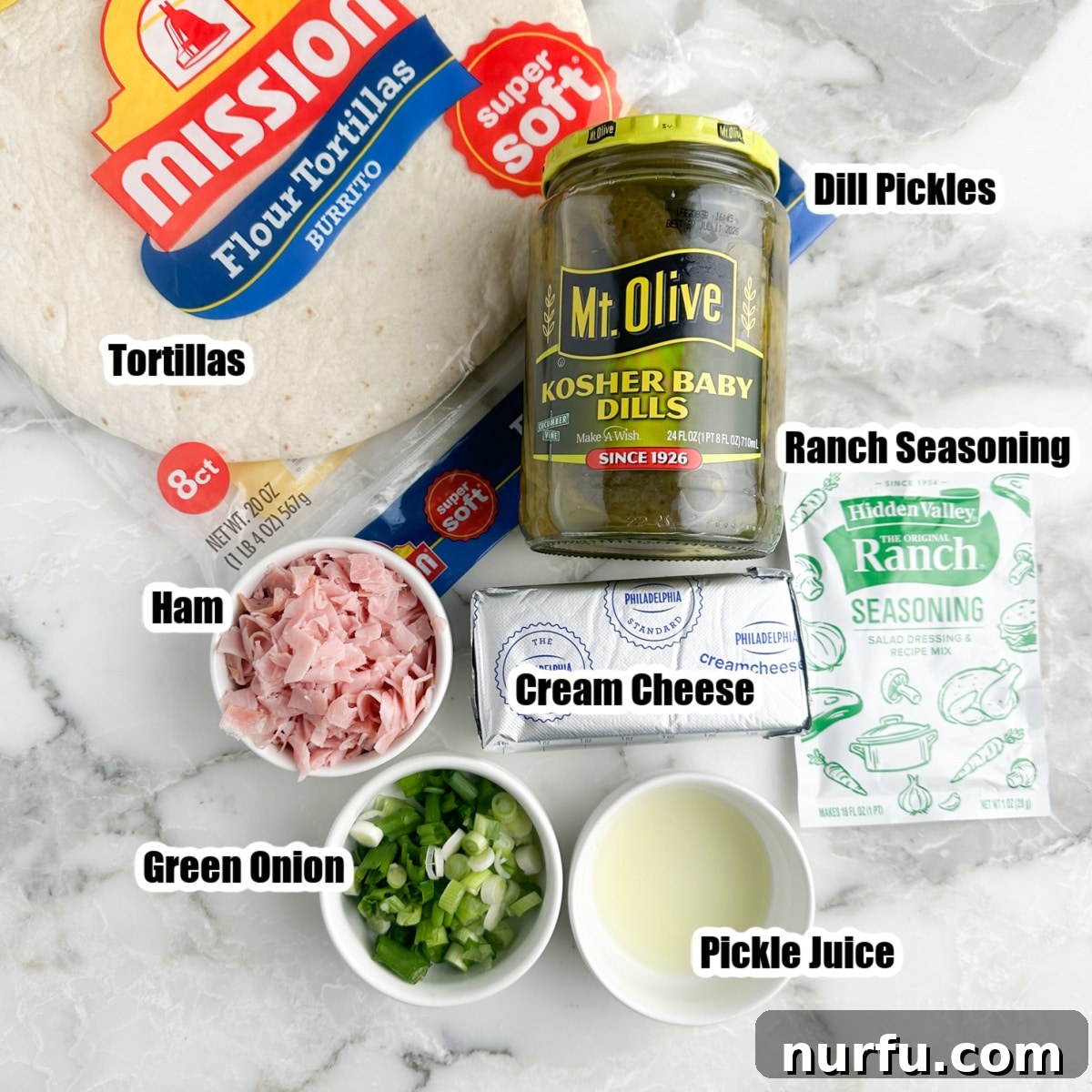 Creamy Dill Pickle Roll-Ups 3 A vibrant flat lay of all the essential ingredients: large flour tortillas, a block of cream cheese, a jar of dill pickles, diced ham, chopped green onions, and a packet of ranch seasoning mix, ready for assembly.