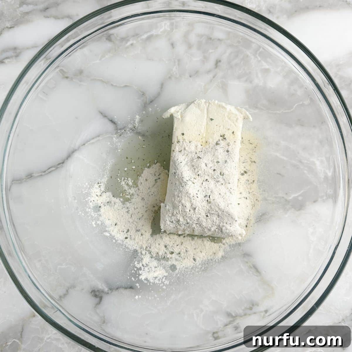 Creamy Dill Pickle Roll-Ups 4 A mixing bowl containing softened cream cheese and a packet of ranch seasoning, ready to be combined into a smooth, flavorful base.