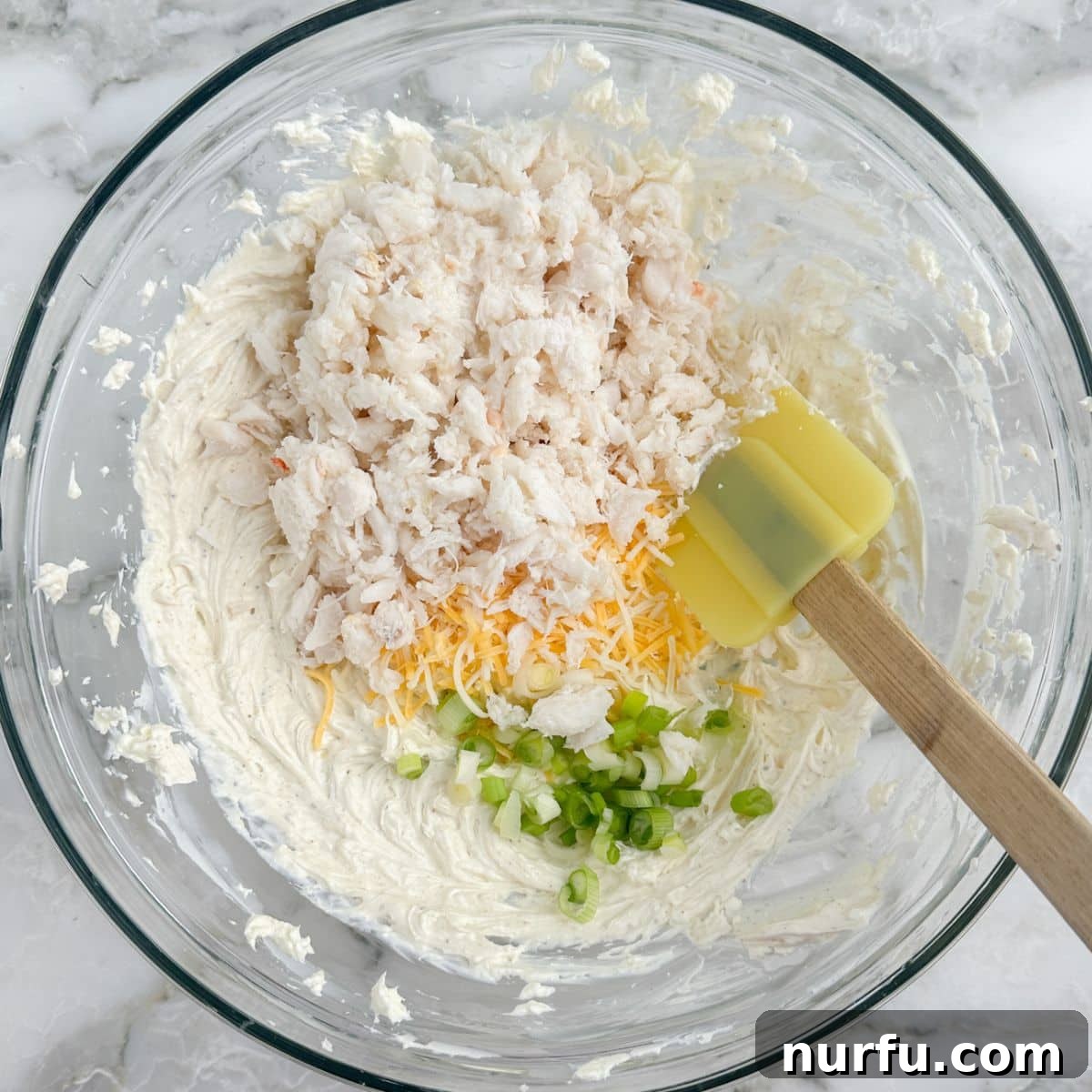 Chilled Crab Delight 6 Mixing bowl with a combination of crab meat, shredded cheese, green onion, and the creamy base, showing the ingredients coming together.