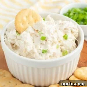 Bowl of crab dip with a Ritz cracker in the dip, showing the creamy texture and inviting appeal.