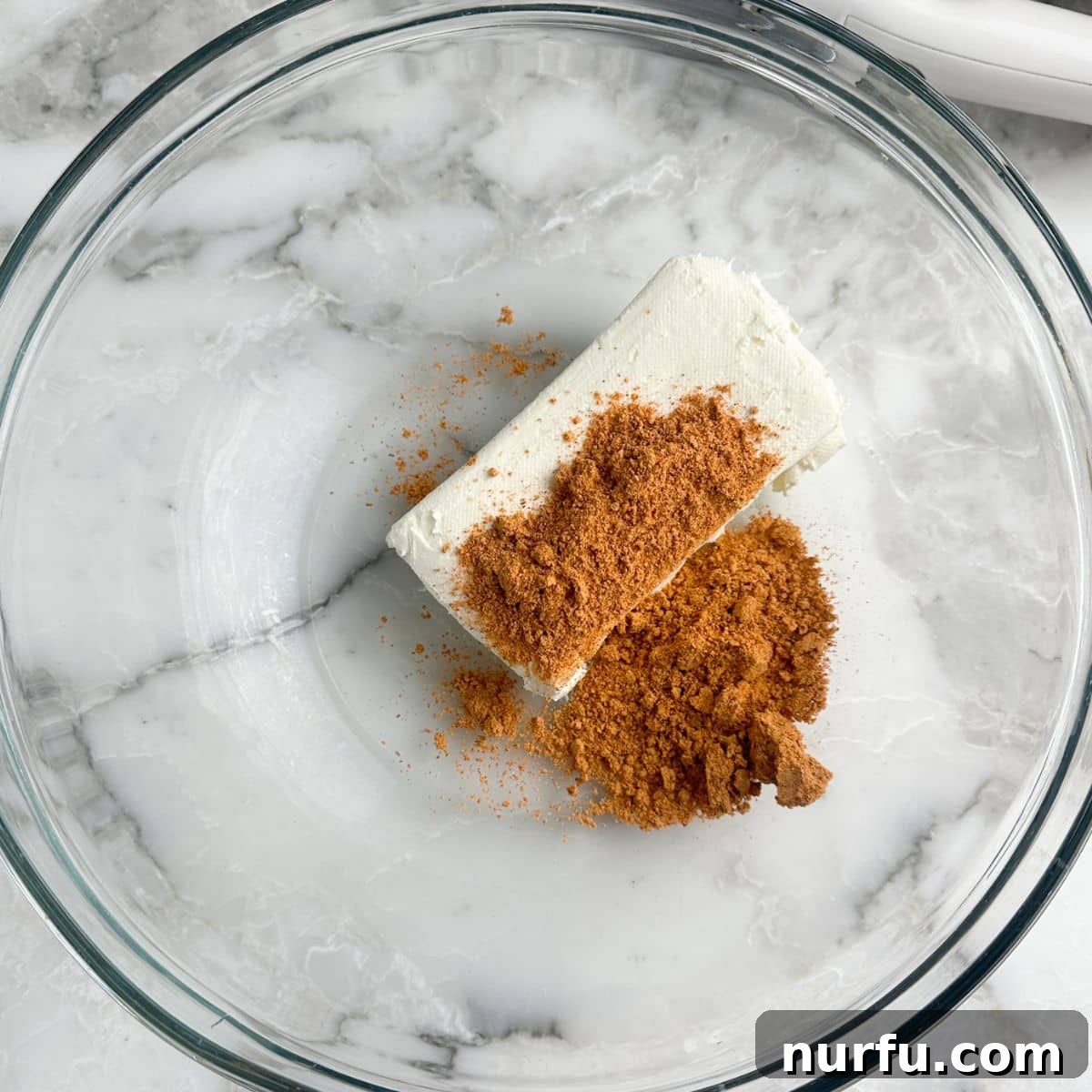 A mixing bowl with softened cream cheese and taco seasoning, ready to be blended for the stuffed pepper filling.