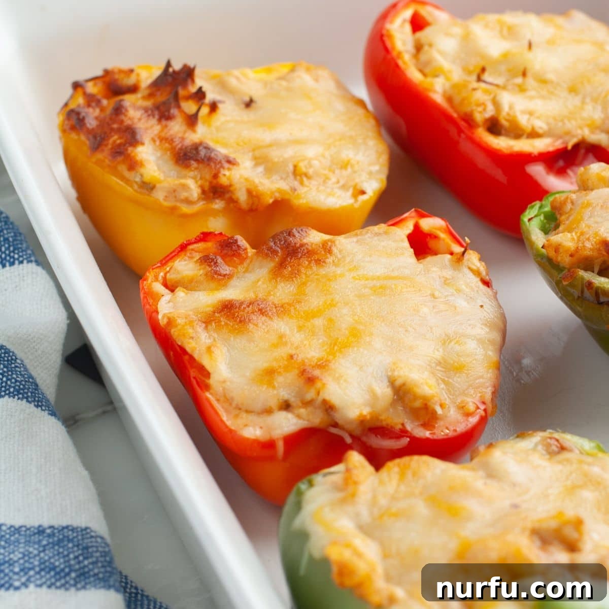Close-up shot of a perfectly baked chicken stuffed bell pepper, featuring bubbly melted cheese and a vibrant, inviting filling.