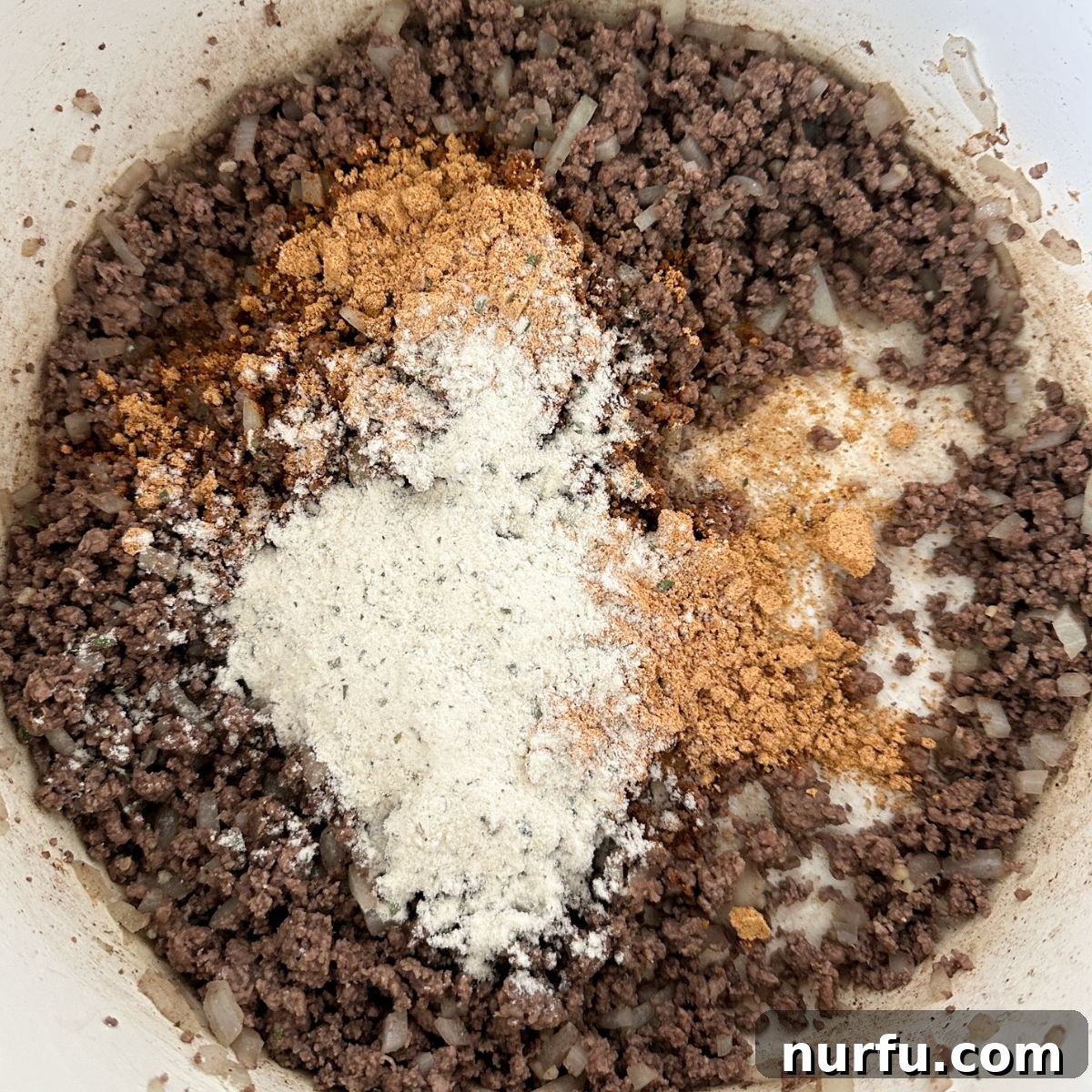 Southwestern Fiesta Soup 4 A large pot on the stovetop containing browned ground beef mixed with diced onions and seasonings, ready for the next ingredients.