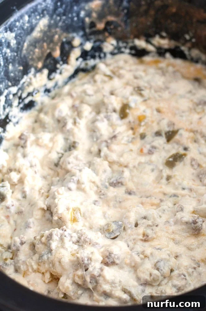 Jalapeño Popper Dip cooking in slow cooker Close-up of creamy Jalapeño Popper Dip simmering in a slow cooker, ready to serve.