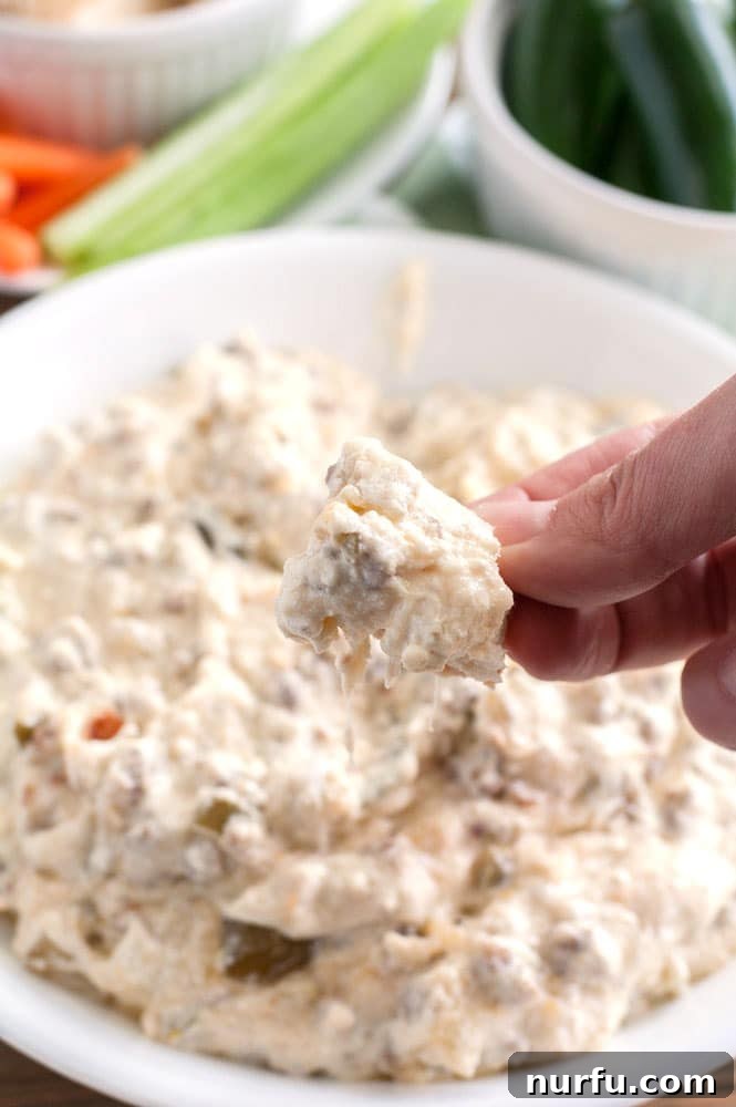 Serving Slow Cooker Sausage Dip Spoon scooping warm, cheesy slow cooker sausage dip from a crock pot, ready to be served.
