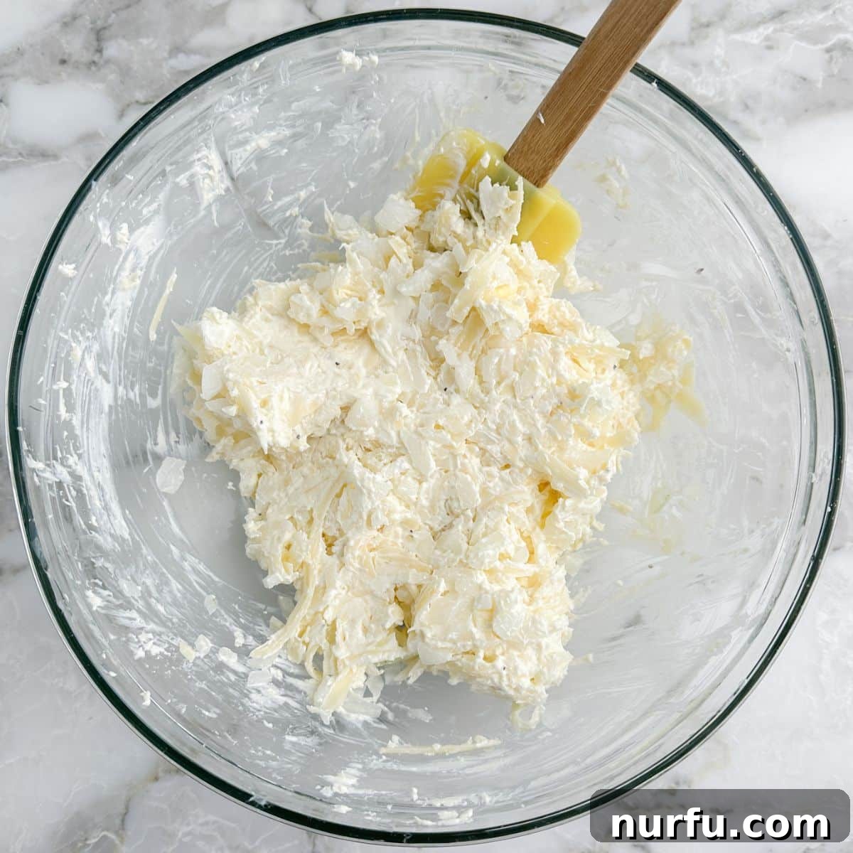 Irresistible Vidalia Onion Dip 6 A bowl filled with the unbaked Vidalia onion dip mixture, with a spatula resting in it, showcasing the creamy texture before baking.
