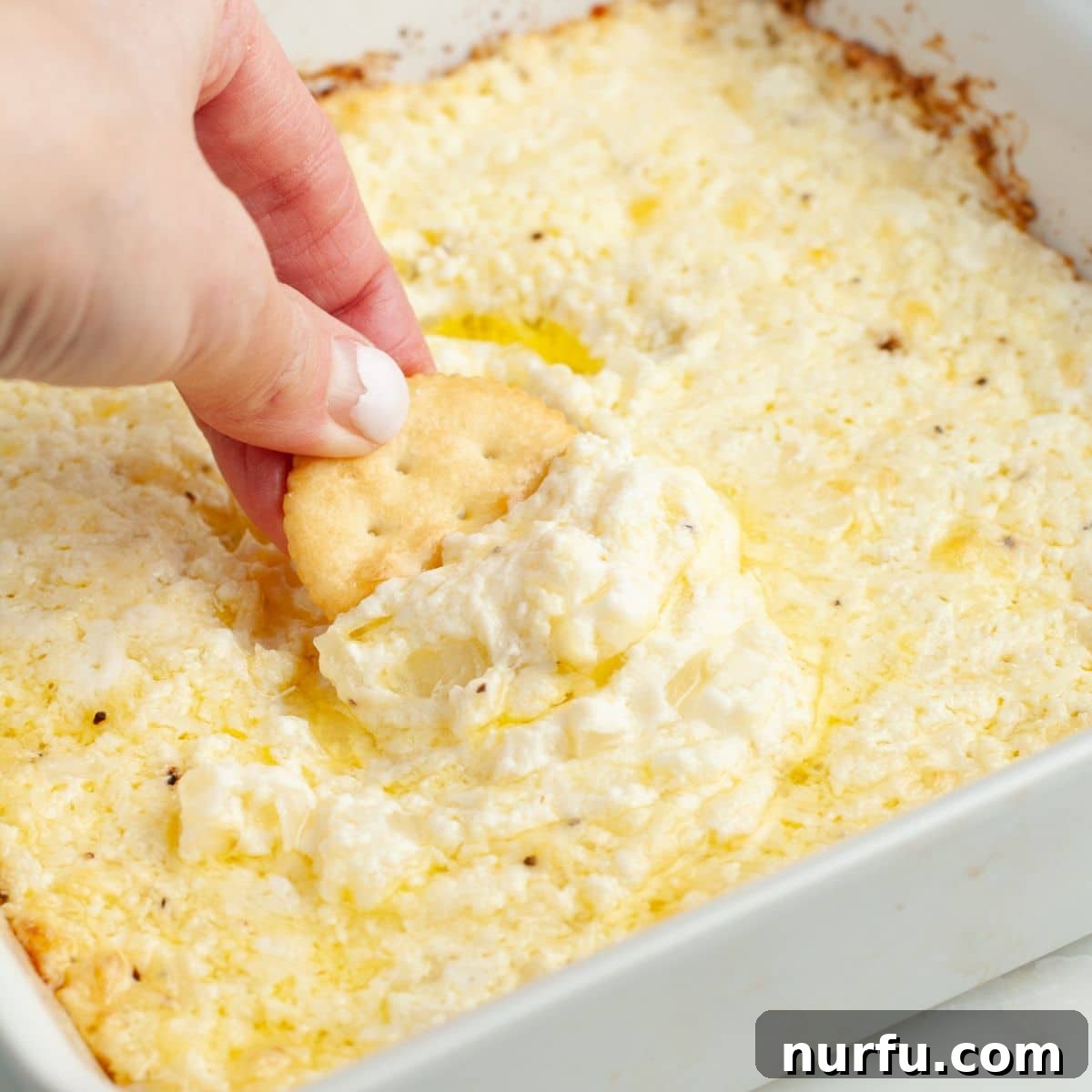 Irresistible Vidalia Onion Dip 8 A cracker loaded with creamy, baked Vidalia onion dip, showcasing its golden-brown top and rich texture, ready to be eaten.