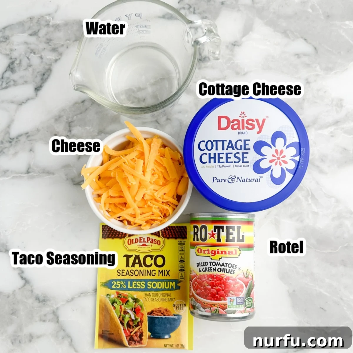 A flat lay photograph showcasing the individual ingredients for cottage cheese queso: a bowl of vibrant shredded cheese, a tub of creamy cottage cheese, a small bowl of taco seasonings, a can of Rotel, and a glass of water.
