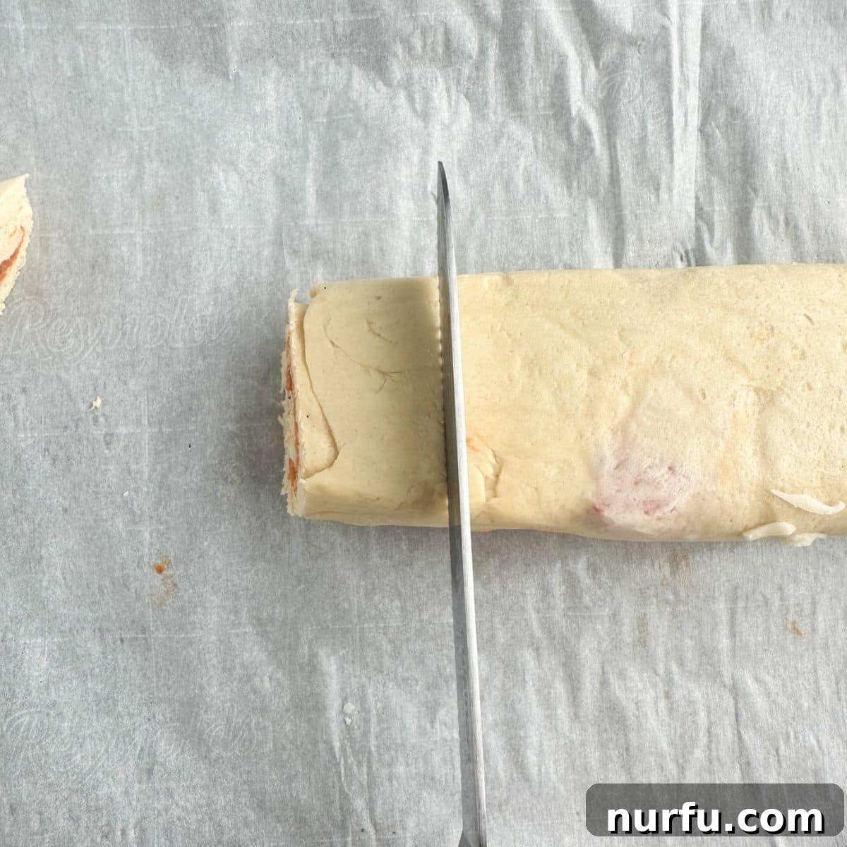 Pepperoni Pizza Swirls 9 A sharp knife neatly slicing a rolled dough log into individual pizza pinwheels, showcasing the perfect spiral layers.