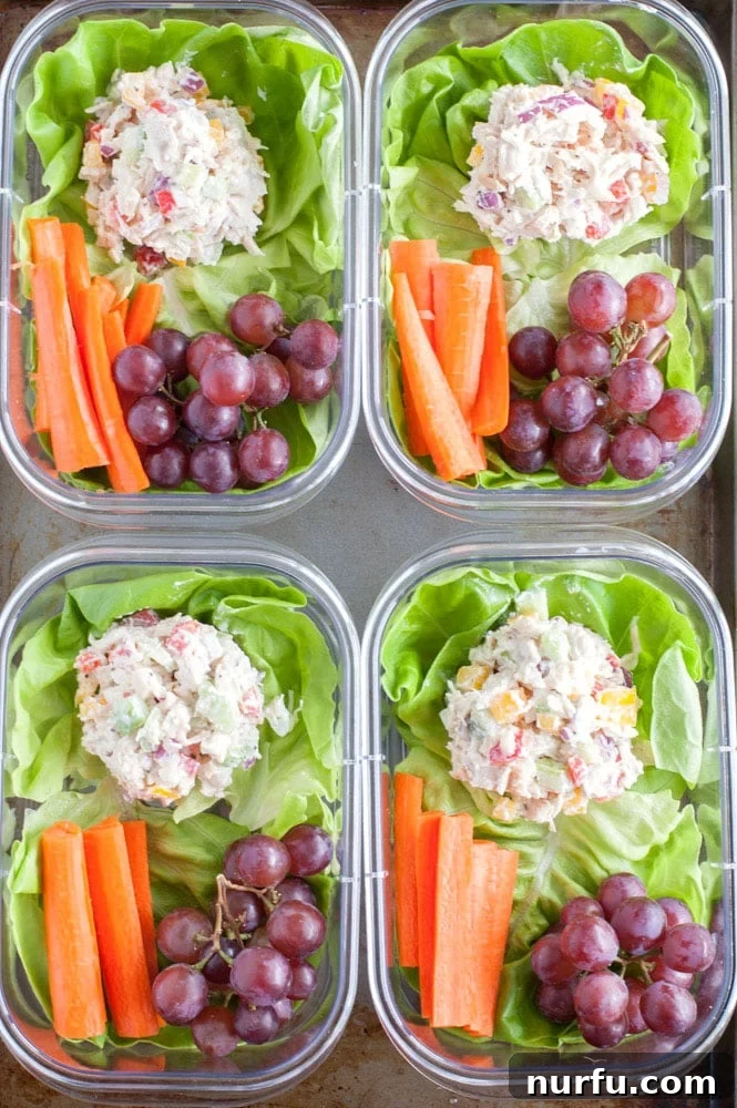 Chicken salad meal prep in four containers with carrots and grapes