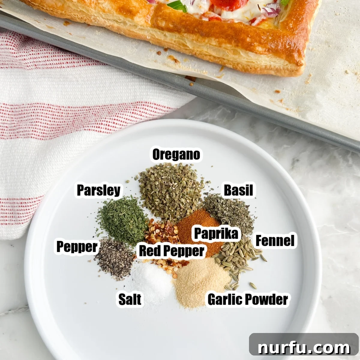 Perfect Homemade Pizza Seasoning Blend 3 Plate displaying individual dried seasonings like basil, oregano, and red pepper flakes before blending.