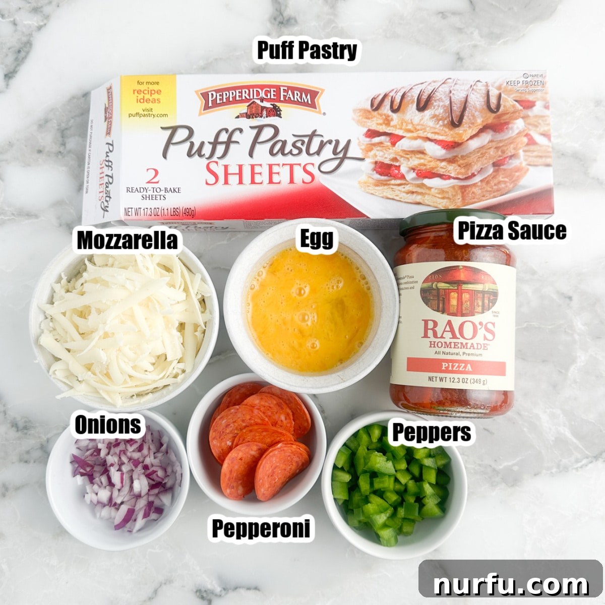 Quick Puff Pastry Pizza 3 Arrangement of puff pastry box, bowl of shredded cheese, an egg, sliced onion, pepperoni, and a bottle of green sauce, representing ingredients.