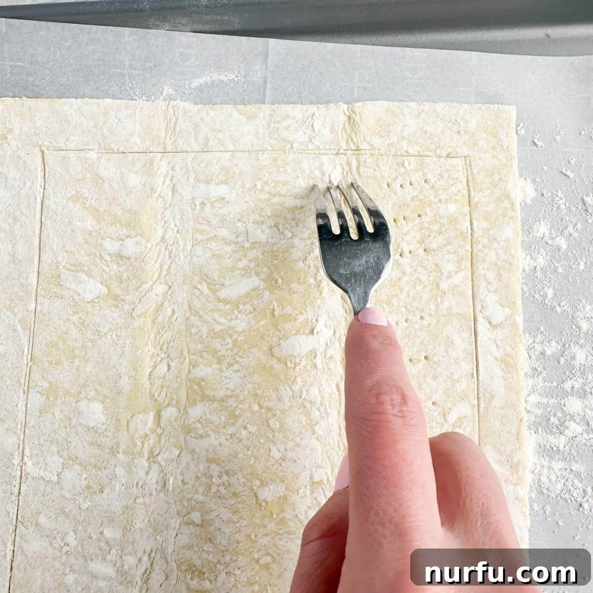 Quick Puff Pastry Pizza 5 A fork pricking the center of puff pastry dough, ensuring even baking and preventing excessive puffing.