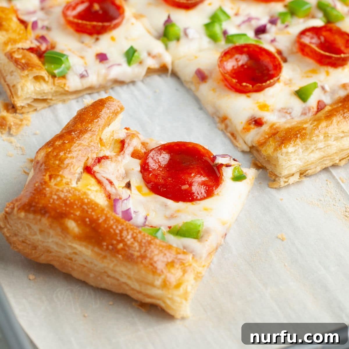 Quick Puff Pastry Pizza 10 A whole puff pastry pizza, fresh from the oven, with golden crust and perfectly melted toppings, resting on a baking pan.