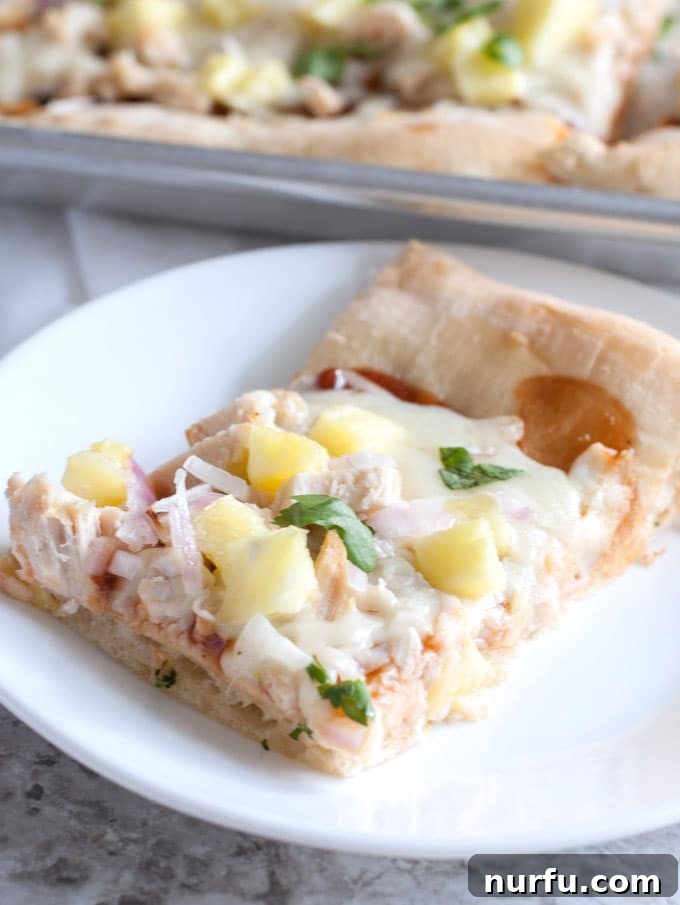 Ready to Enjoy: A Perfect Slice A slice of sheet pan BBQ chicken pizza on a white plate, showcasing the crispy crust and delicious toppings.