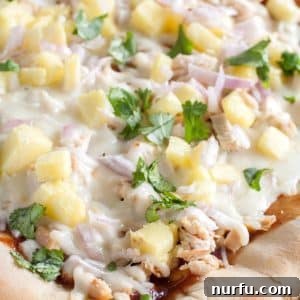 Pizza on baking dish with chicken, cheese and pineapple.