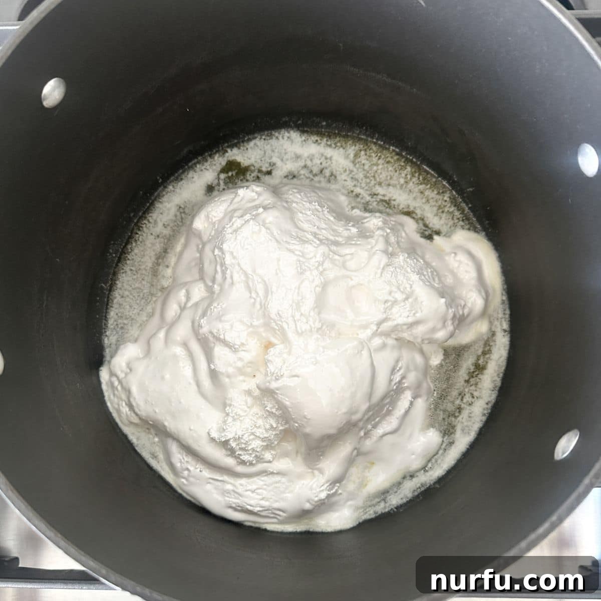 Cloud Nine Krispie Treats 4 A large pot on a stove with melted butter and marshmallow fluff being stirred together.