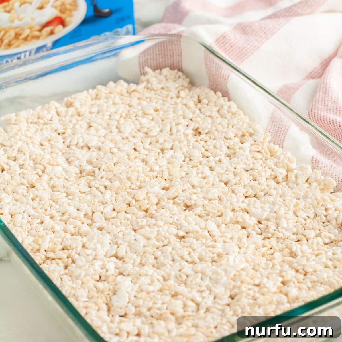 Cloud Nine Krispie Treats 7 A baking dish filled with settled Rice Krispie treats, covered and resting.