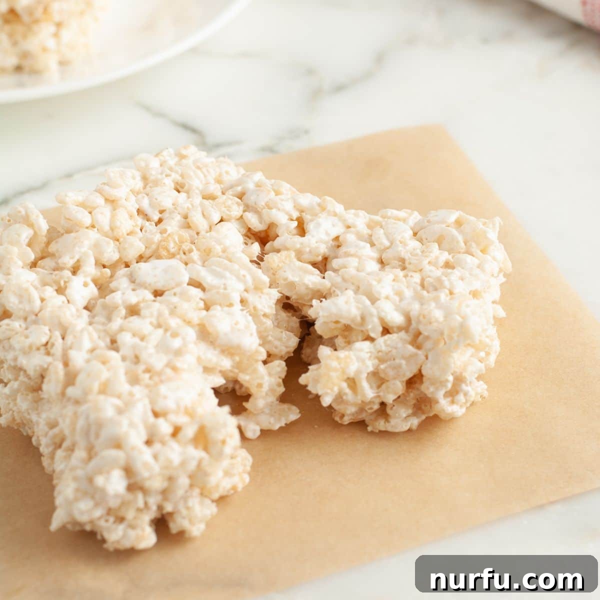 Cloud Nine Krispie Treats 8 A single Rice Krispie treat square sitting on a rustic wooden table, showcasing its gooey texture.