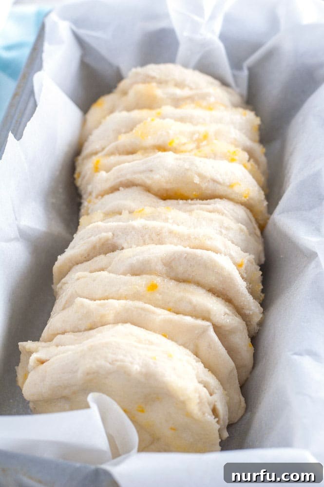 Easy Orange Bread Layers Side view of glazed orange pull apart bread pieces in a loaf pan