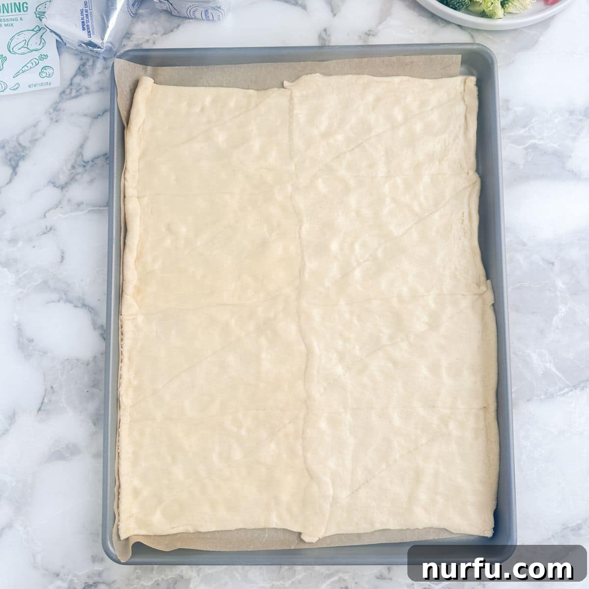Flaky Garden Veggie Bake 4 Unrolled crescent roll dough flattened on a baking pan, with seams pinched together.