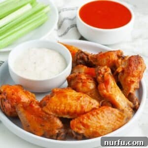 Plate of chicken wings with ranch, celery sticks, and buffalo sauce.