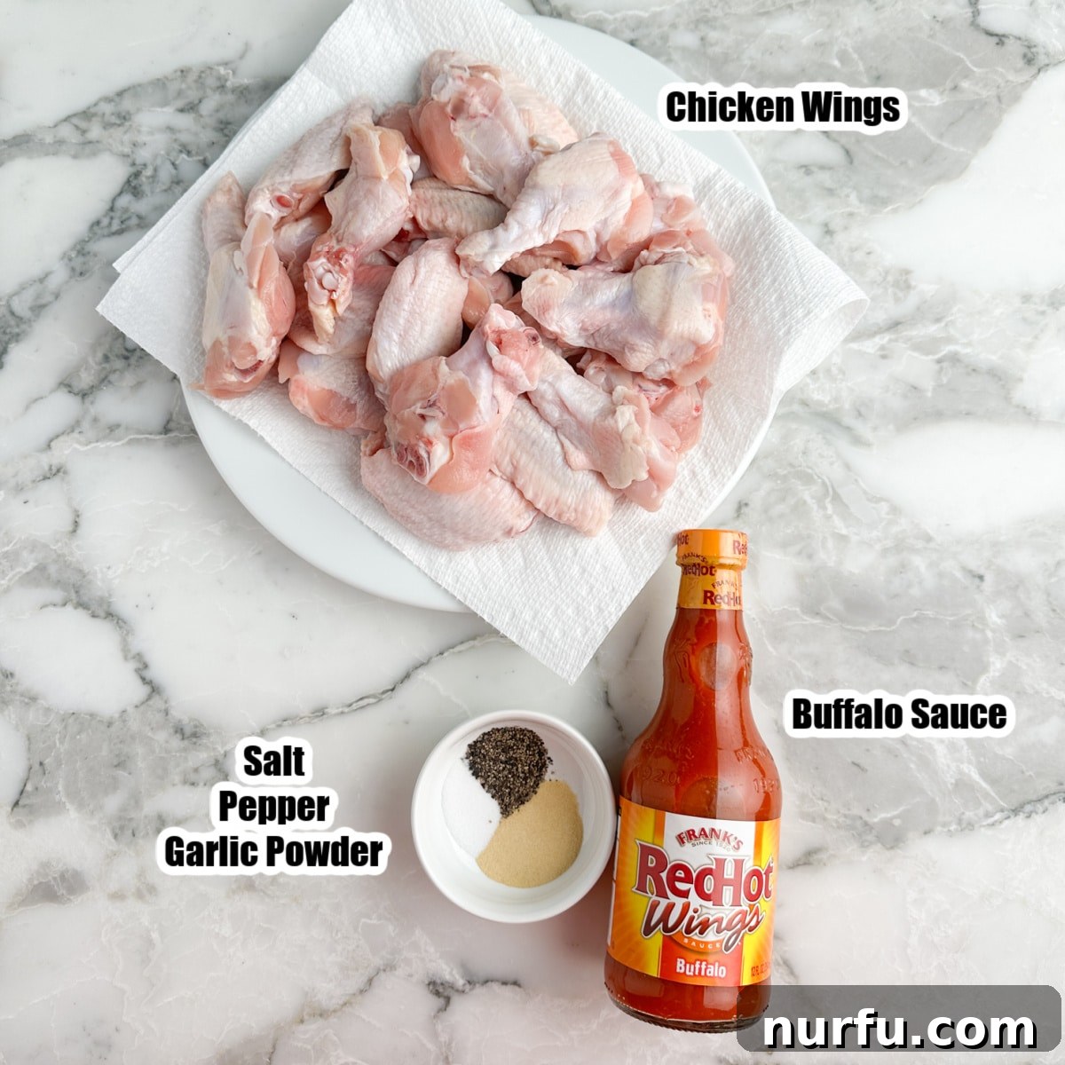 Effortless Slow Cooker Chicken Wings 3 A bowl of uncooked chicken wings alongside a bottle of buffalo sauce and a small bowl of mixed seasonings.