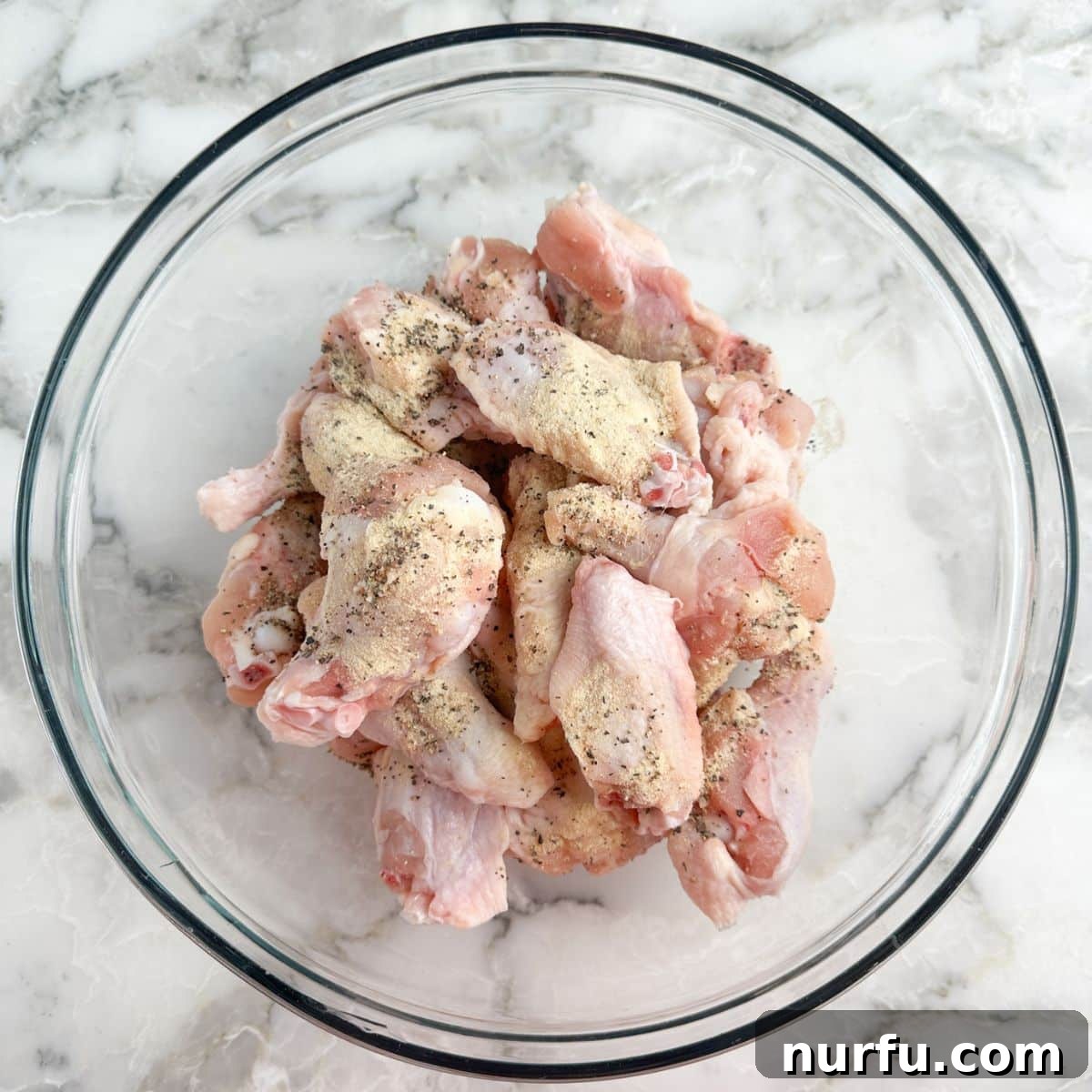 Effortless Slow Cooker Chicken Wings 5 A large bowl filled with uncooked chicken wings, ready for seasoning.