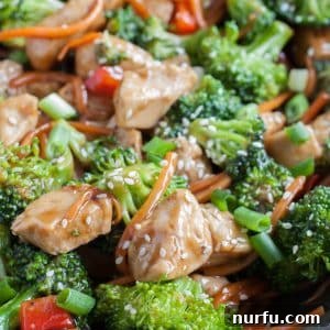 Cooked chicken, broccoli and carrots in a skillet, coated in teriyaki sauce.