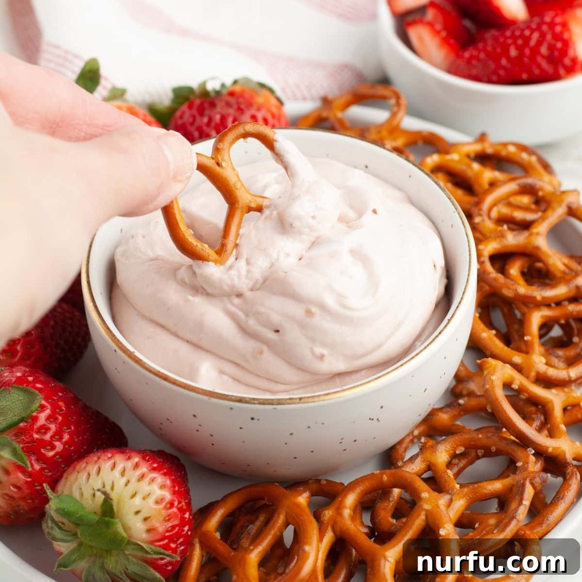 Strawberry Bliss Dip 6 Bowl of strawberry dip with a single pretzel ready for dipping.