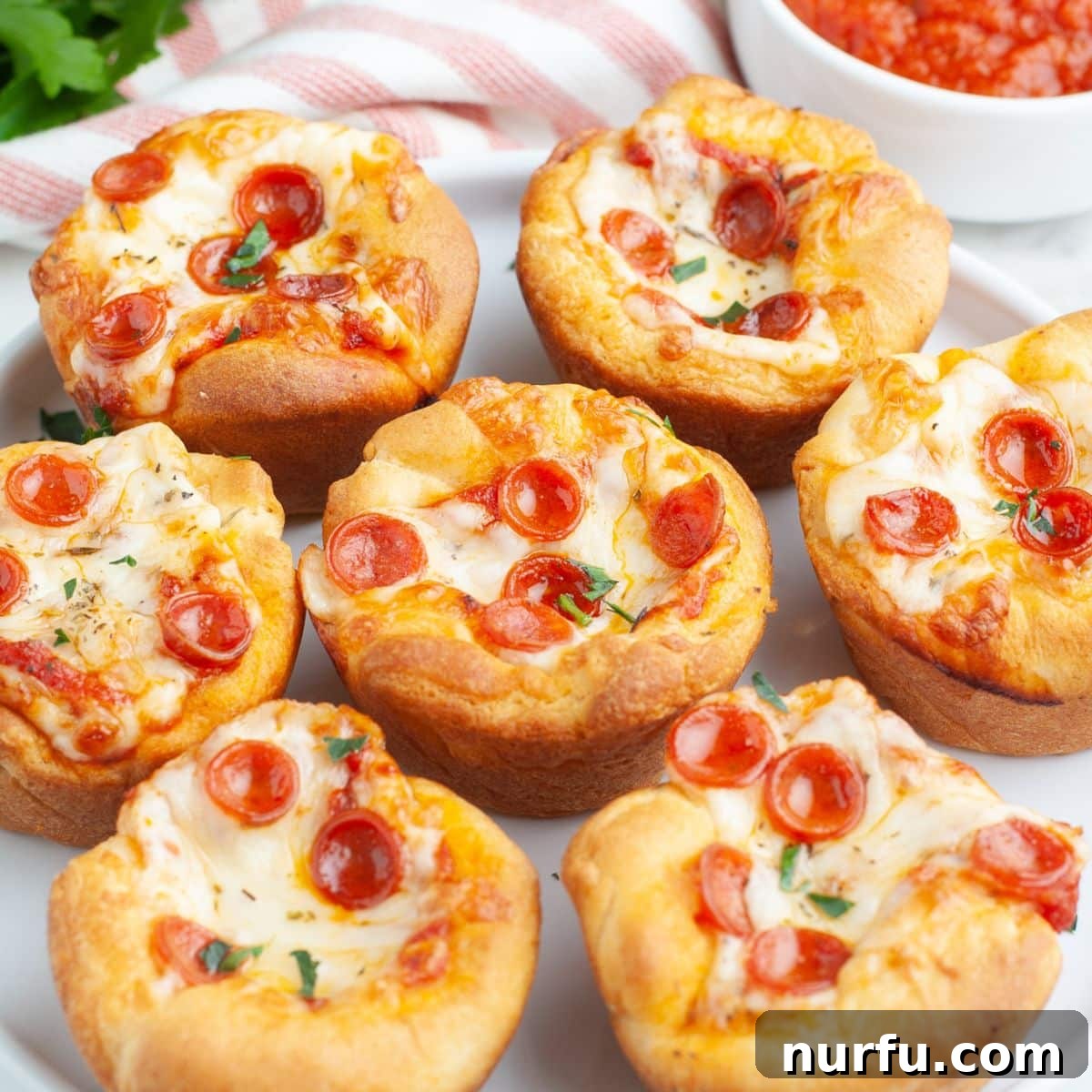 A serving plate filled with freshly baked, golden-brown pepperoni pizza cupcakes, ready to be enjoyed as a snack or meal.