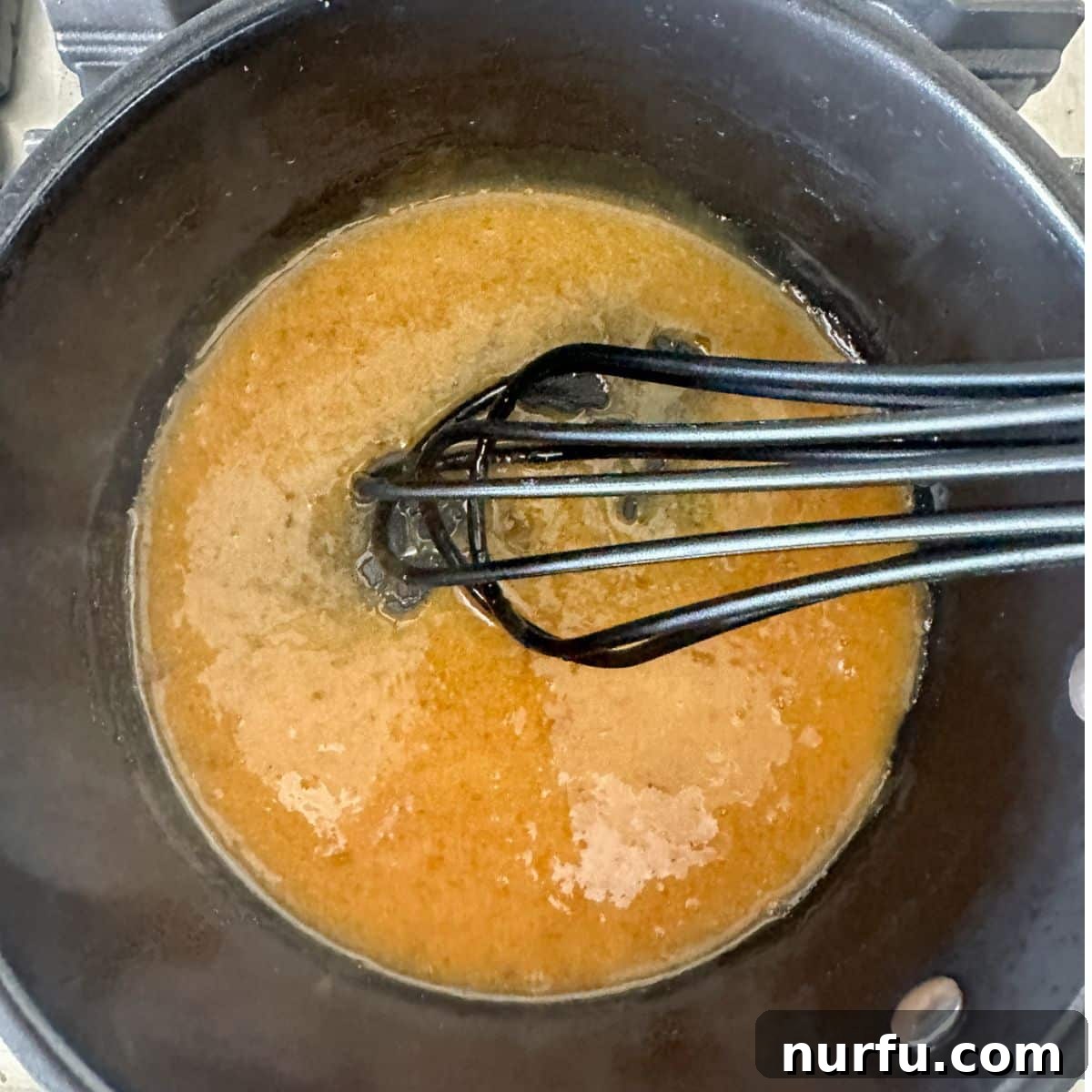 Perfect Homemade McDonalds Sweet and Sour Sauce 5 Saucepan with sauce and a whisk.