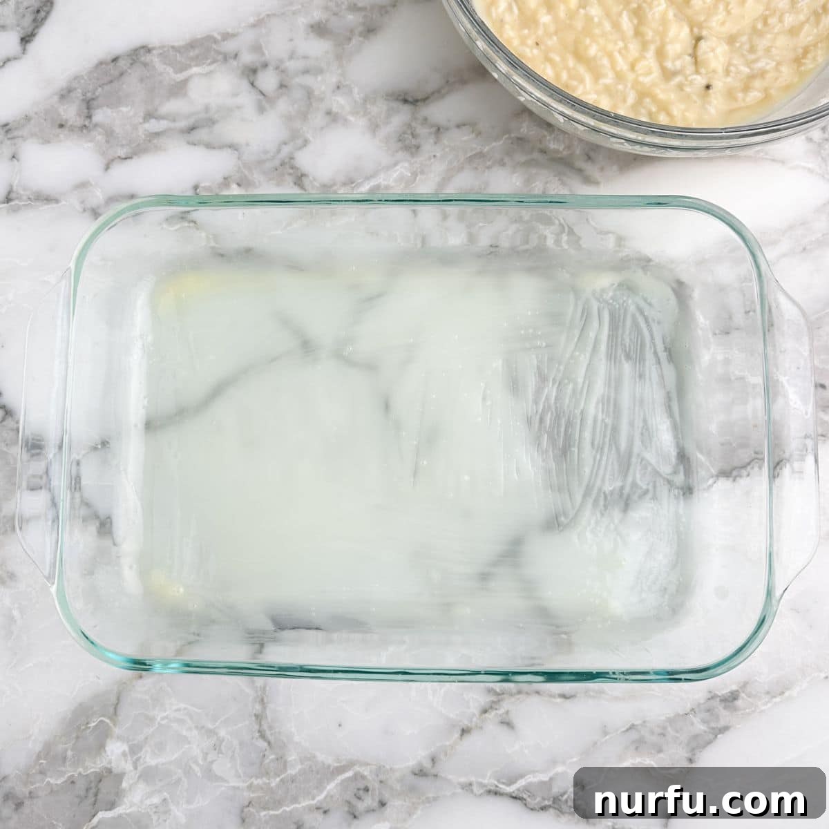 The Chicken That Time Forgot 4 A pristine glass baking dish with a thin, glistening layer of melted butter spread across its bottom, ready for the next step of the recipe.