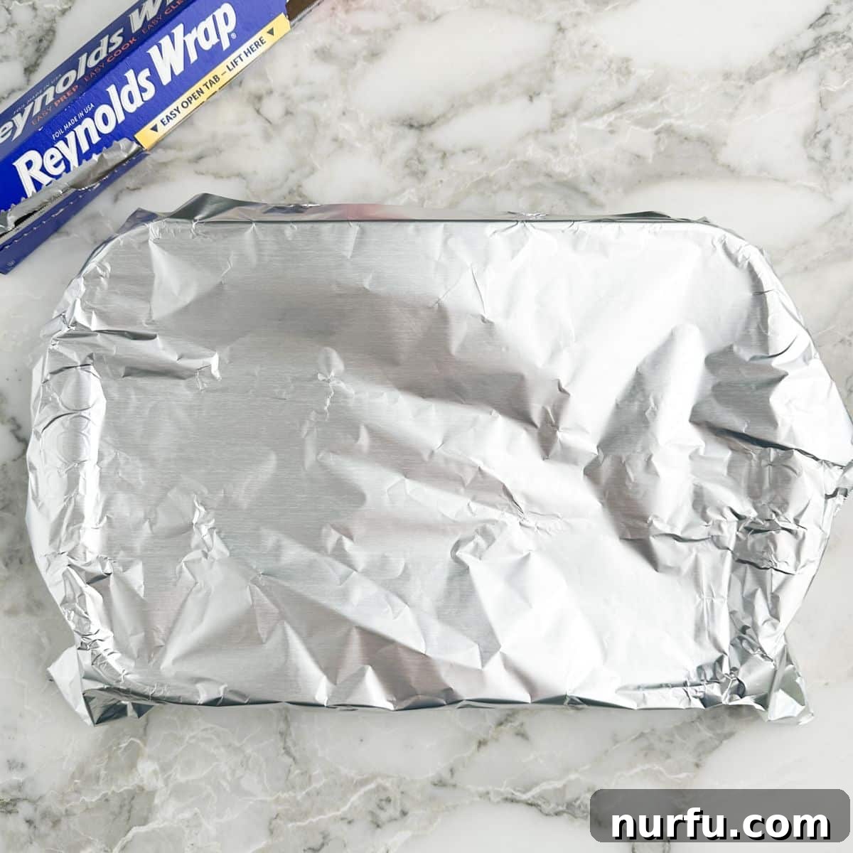 The Chicken That Time Forgot 7 The baking dish fully covered with a sheet of aluminum foil, sealing in the moisture and flavors for the 'forgotten' cooking process.