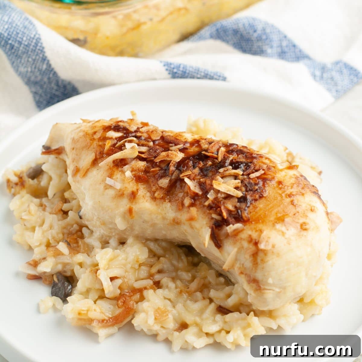 The Chicken That Time Forgot 8 A serving of Forgotten Chicken on a white plate, showcasing the perfectly cooked chicken breast on a bed of creamy rice, garnished with fresh parsley.