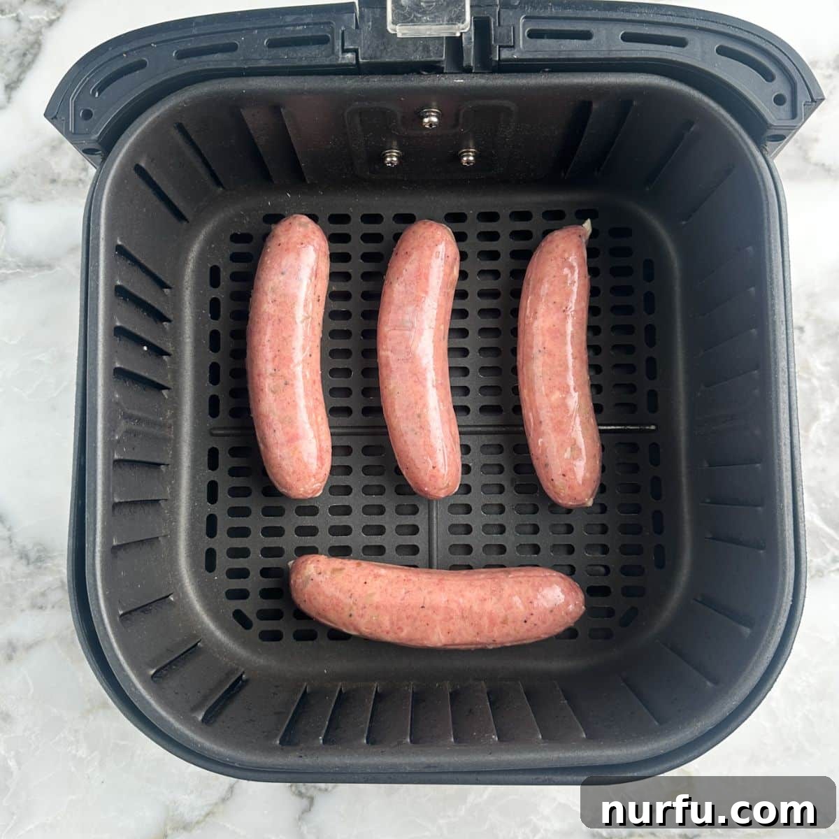 Perfectly Crispy Air Fryer Chicken Sausage 4 Air fryer basket with uncooked chicken sausages arranged neatly.