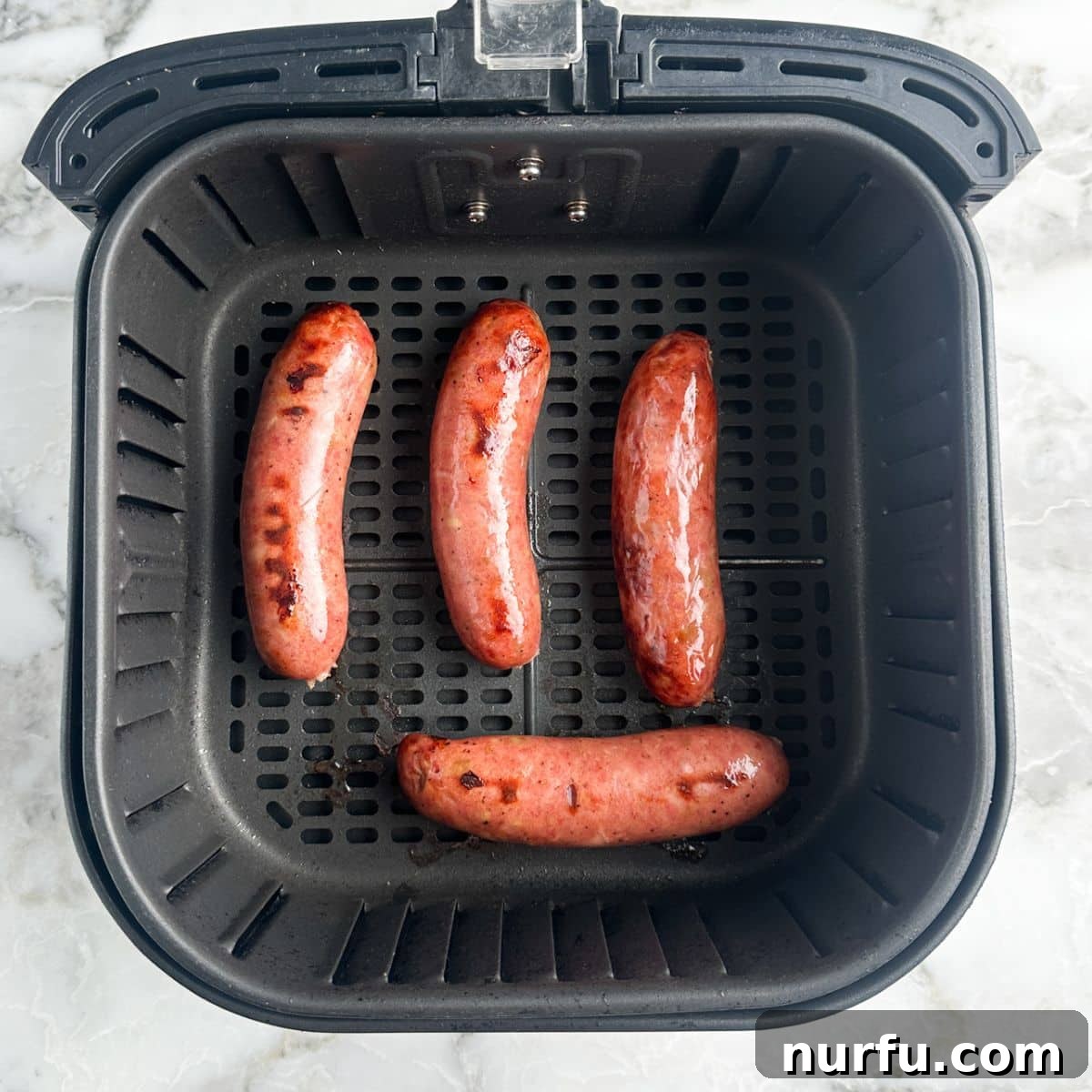 Perfectly Crispy Air Fryer Chicken Sausage 5 Cooked chicken sausages with a golden-brown finish in the air fryer basket.