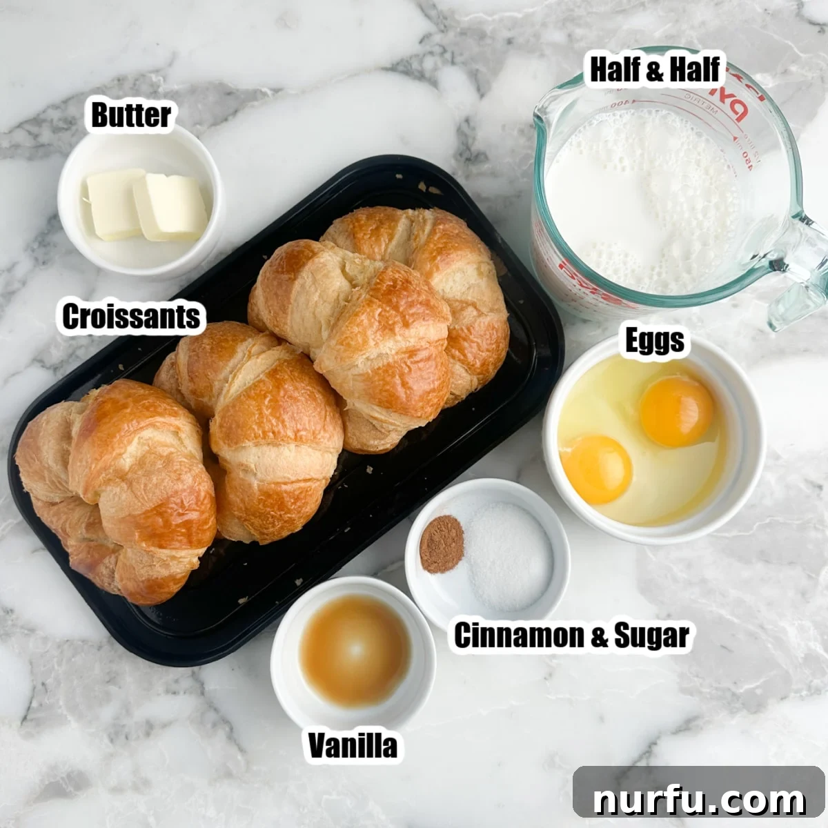 Pâtisserie French Toast 3 Ingredients for croissant French toast laid out: day-old croissants, a bowl of butter, milk, eggs, vanilla extract, sugar, and ground cinnamon.