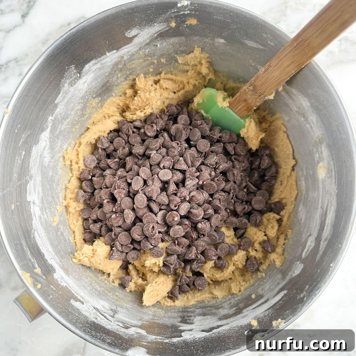 Gooey Brown Sugar Congo Bars 5 A mixing bowl filled with golden-brown cookie dough, generously studded with semi-sweet chocolate chips.