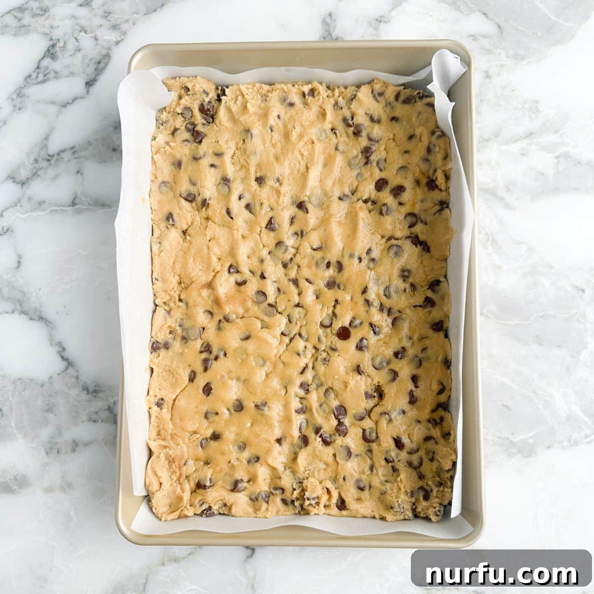 Gooey Brown Sugar Congo Bars 7 Unbaked chocolate chip cookie dough spread evenly in a baking pan, ready for the oven.