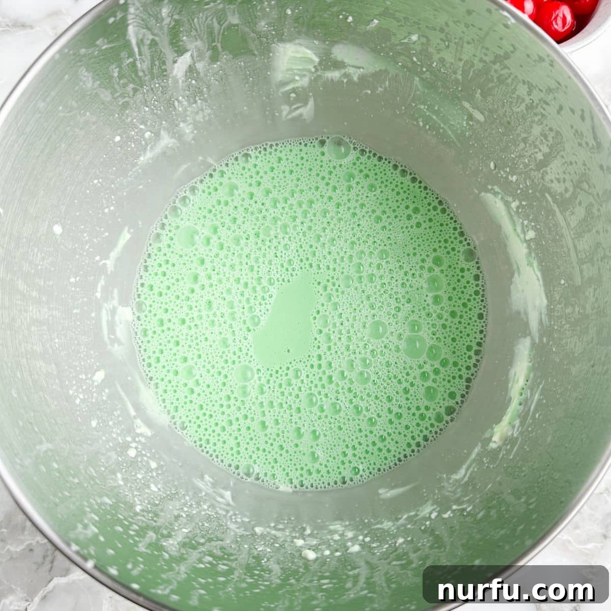 Sea Mist Salad 4 A mixer bowl containing green JELL-O and softened cream cheese, thoroughly mixed into a smooth, pale green mixture.