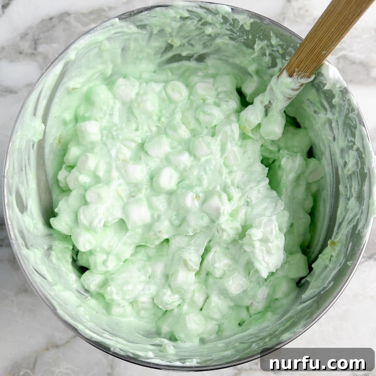 Sea Mist Salad 6 A mixer bowl showing the creamy green mixture now combined with mini marshmallows, creating a fluffy and textural appearance.