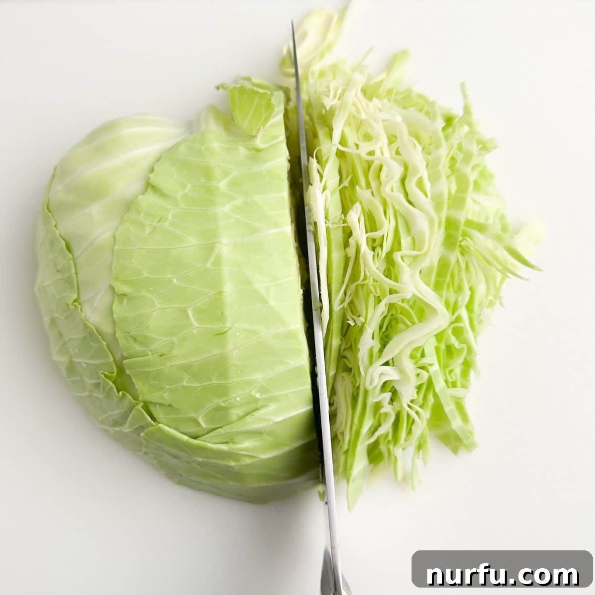Bold Blue Coleslaw 4 A sharp knife carefully cutting into a head of fresh cabbage on a wooden cutting board, preparing it for shredding.