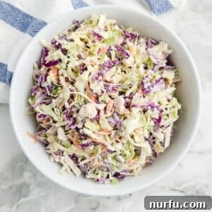 A beautifully presented bowl of creamy blue cheese coleslaw, garnished and ready to be served. The rich texture and vibrant colors highlight its delicious appeal.
