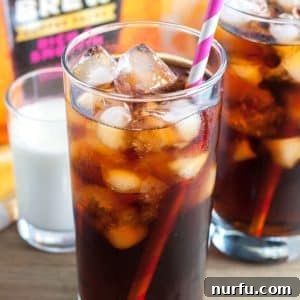Tall glass of iced coffee with pink straw.