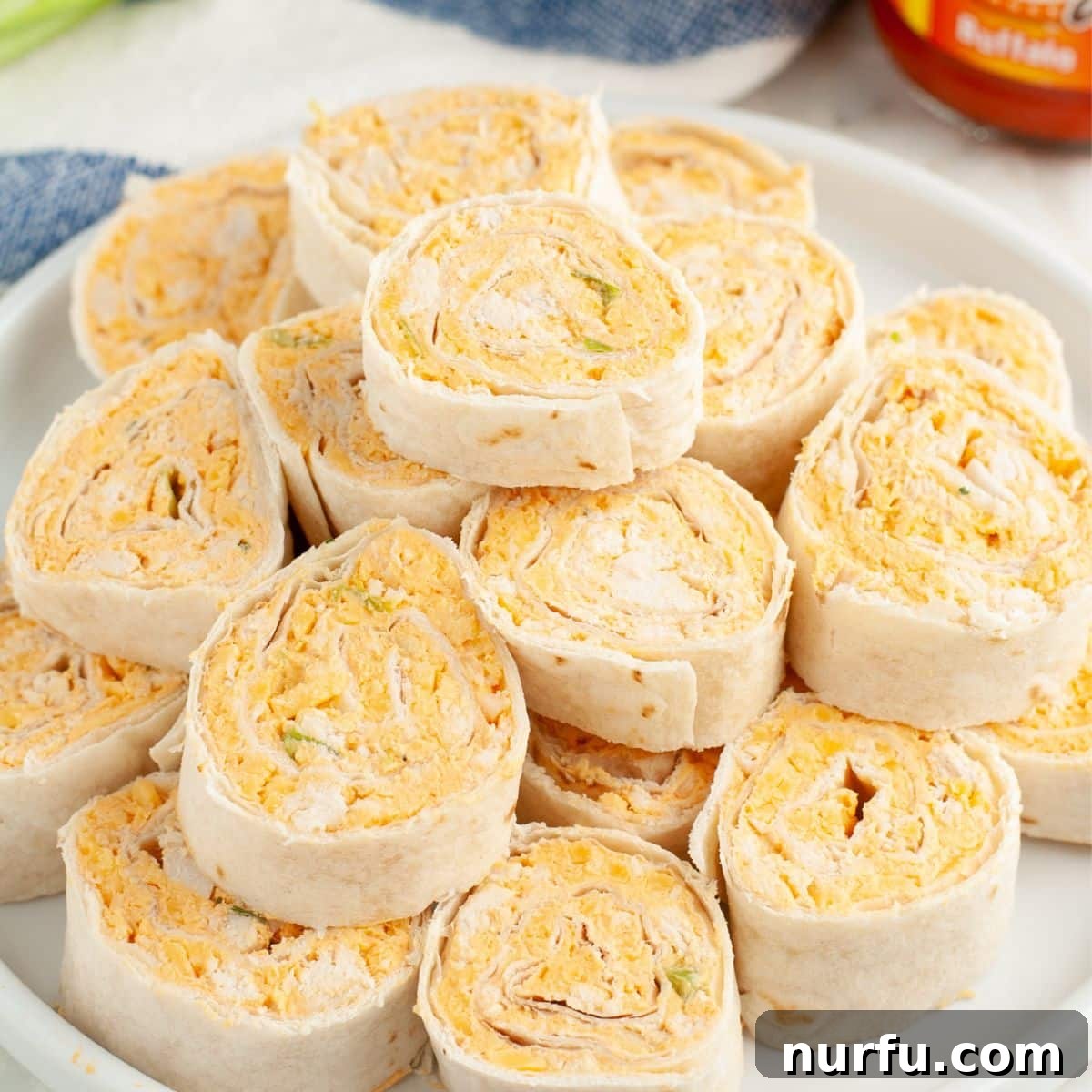 A beautifully arranged plate of freshly sliced Buffalo Chicken Pinwheels, garnished with a sprinkle of green onions, ready to be served.